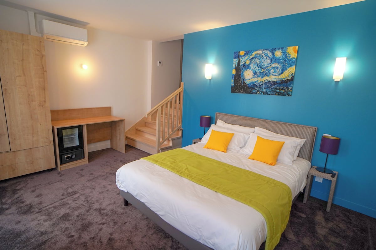 Une chambre à coucher avec un lit, un tableau au mur et un escalier.