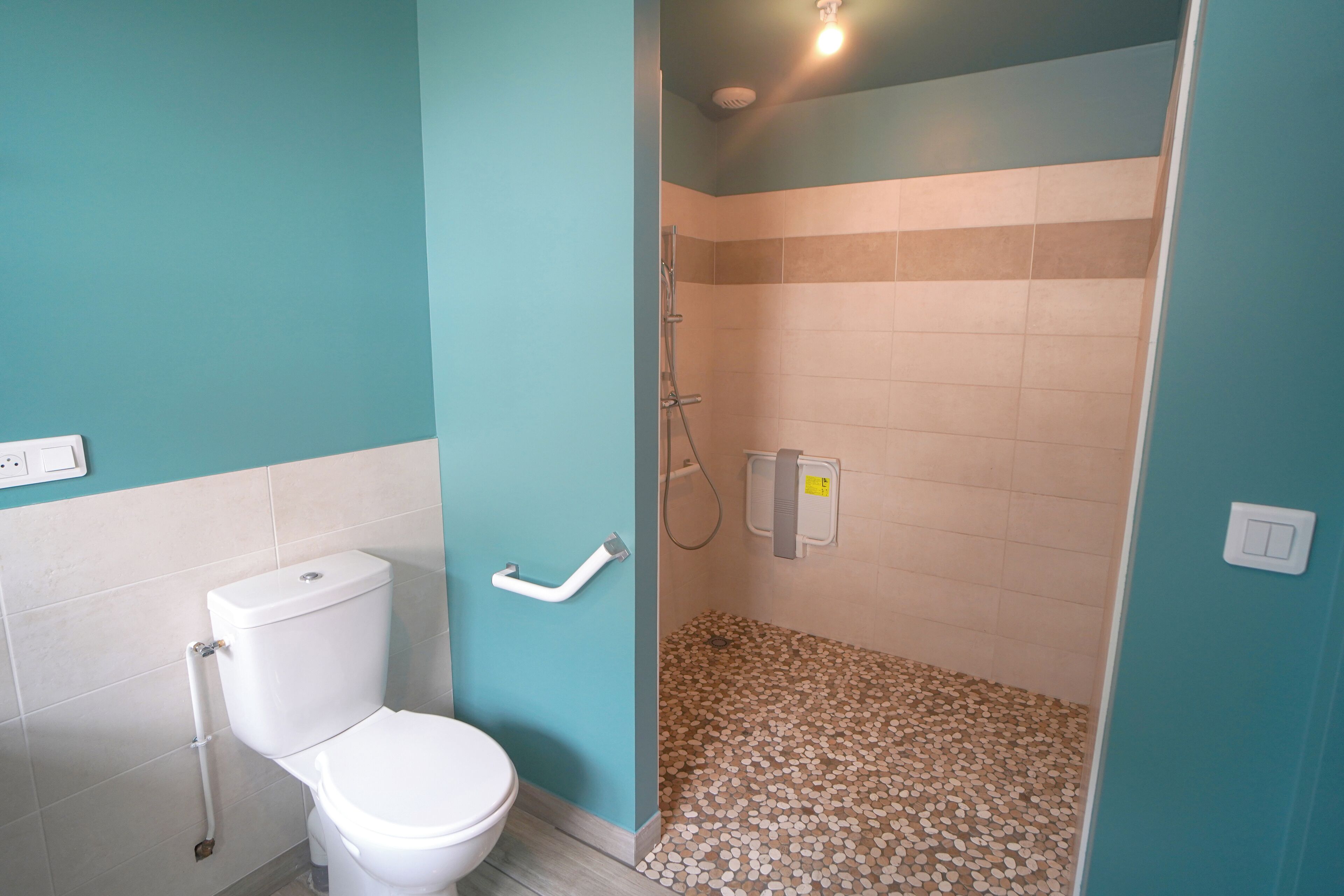 Ein Badezimmer mit Toilette, Dusche und Fliesenboden.