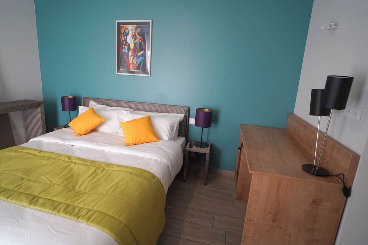 Une chambre à coucher avec un lit, deux tables de chevet, une commode, une lampe et un tableau au mur.