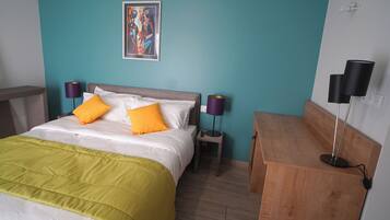 A bedroom with a bed, two bedside tables, a nightstand, a lamp, and a painting on the wall.