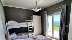 Un dormitori amb un llit superposat, un armari i una finestra gran amb cortines.