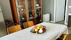 Zona de dinar amb una taula ben posada per a quatre persones, un armari de fusta amb portes de vidre i una porta que condueix a una altra estança.