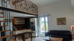 Eine moderne Küche mit Essbereich, einer Treppe und einem Wohnzimmer mit Sofa und Gemälde.