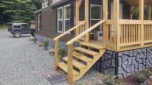 A two-story cabin with a wooden deck and a stone foundation. - Rustic Mountain Cabin 225 (Topton)