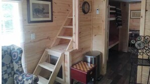 A wooden interior with a ladder, a framed picture, and a small table with a chessboard. - Rustic Mountain Cabin 225 (Topton)