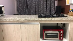Une cuisine équipée d’un four à micro-ondes, d’une cuisinière à gaz et d’un grille-pain rouge.
