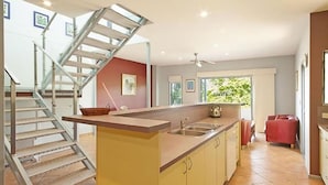 A modern kitchen with a central island, a built-in sink, and a staircase leading to an upper level.