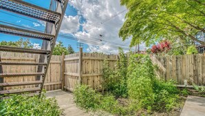 A backyard with a wooden fence, a metal structure, and various plants. - Charles Village 1-BR, Walk to Johns Hopkins (Baltimore)