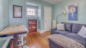 A cozy room with a wooden table, a bookshelf, a grey sofa, and a framed picture on the wall. - Charles Village 1-BR, Walk to Johns Hopkins (Baltimore)