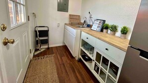 Een kleine keuken met witte kasten, een houten aanrecht, een ingebouwde oven en een klein spoelbakje.