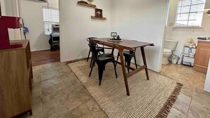 Een eethoek met een houten tafel en stoelen, een vloerkleed en een klein plankje met decoratieve objecten.