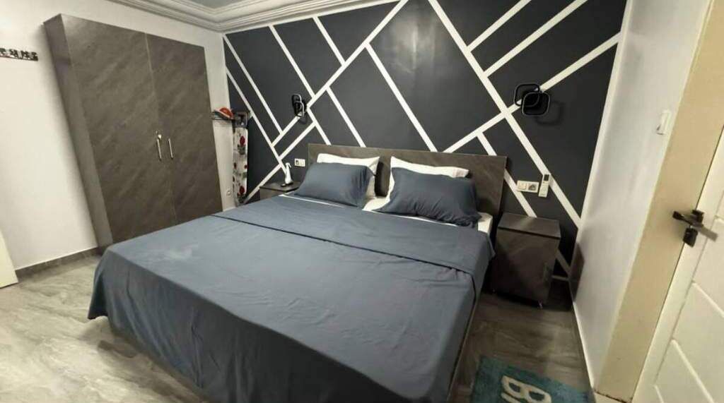 A bedroom with a bed, nightstands, and a wardrobe.