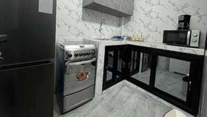 Une cuisine de taille réduite équipée d’un réfrigérateur, d’une cuisinière, d’un four, d’un four à micro-ondes et d’un placard.