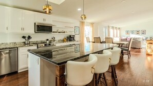 A modern kitchen with white cabinets, a central island with bar stools, stainless steel appliances, and pendant lighting. - Stunning View, Fully Stocked Kitchen Near Wineries (Grants Pass)
