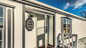 A single-story building with a white exterior, a front door, and a small porch with a railing. - Stunning View, Fully Stocked Kitchen Near Wineries (Grants Pass)