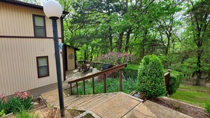 Una casa a due piani con un balcone immersa nel verde e alberi.