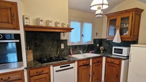 A kitchen with wooden cabinets, a built-in oven, a microwave, and a sink.