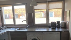 Una cocina compacta con lavadora, cafetera y lavabo.