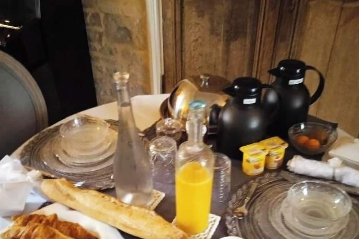 A breakfast table with croissants, a bottle of orange juice, and a coffee setup.