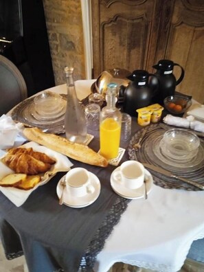 Una mesa de desayuno con croissants, una botella de jugo de naranja y una cafetera.