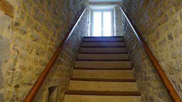 Una escalera de piedra con barandillas de madera que conduce a un ventanal luminoso en la parte superior.