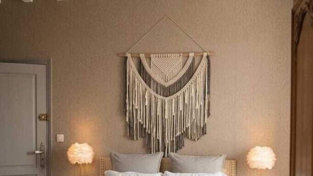 Un dormitorio con cama, dos mesitas de noche, un colgador de macramé y techo de madera.