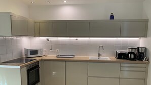A modern kitchen with a built-in oven, microwave, and a coffee maker.