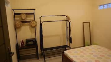 A small, simple room with a bunk bed, a desk with a chair, a hat rack, and a mirror on the wall.
