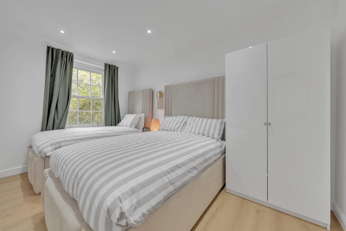 Une chambre moderne avec deux lits, une grande armoire et une fenêtre avec des rideaux.
