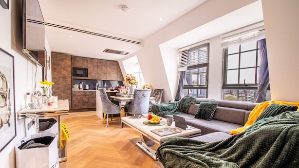 Una sala de estar moderna con sofá, mesa de centro y zona de comedor.