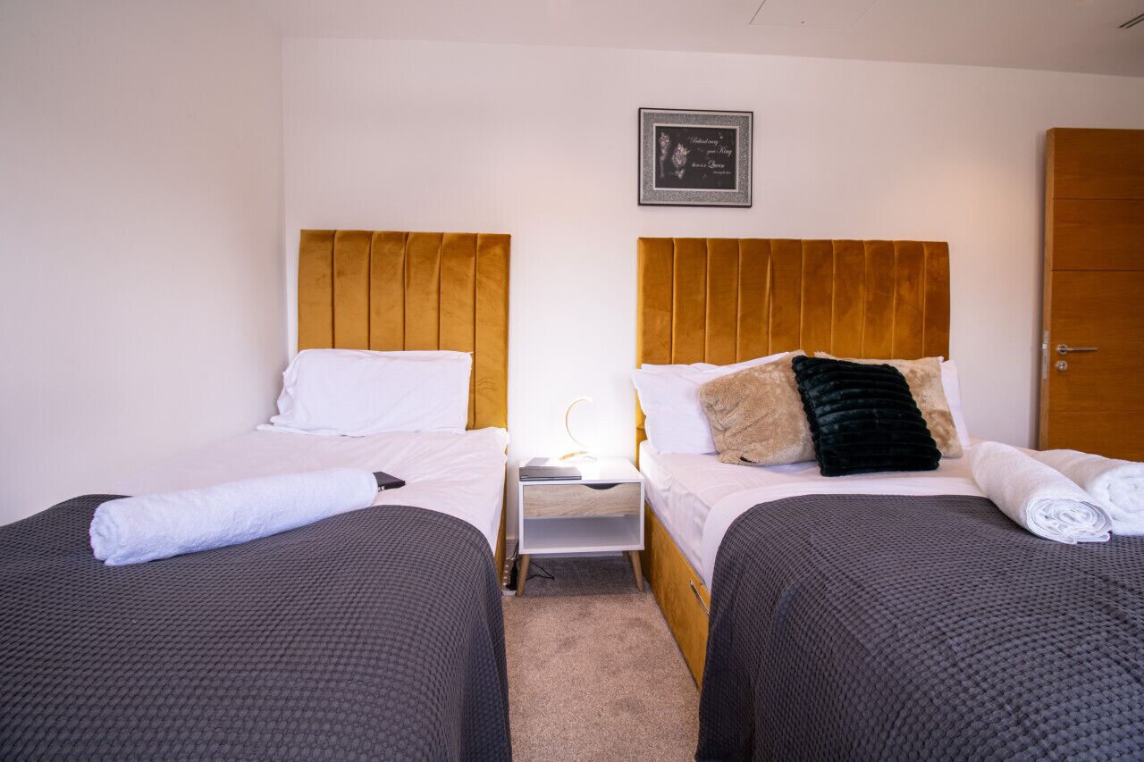 A hotel room with two beds, each with a wooden headboard, a nightstand, and a framed picture on the wall.