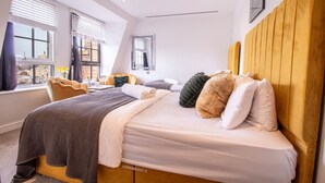 Una habitación de hotel moderna con una cama grande, vistas a la ciudad y una ventana con persianas.