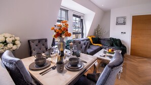 Un comedor con una mesa dispuesta para dos personas, un sofá y una ventana con persianas.