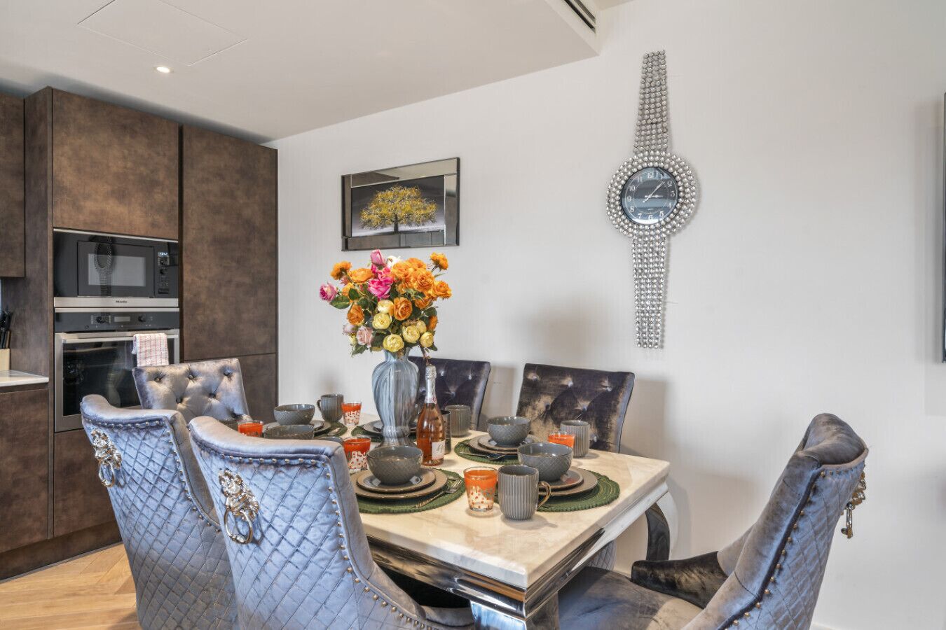 Un espace de salle à manger moderne, avec une table en marbre, des chaises rembourrées et un élément décoratif mural.