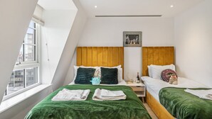 Una habitación de hotel moderna con dos camas, un ventanal grande y vistas a la ciudad.
