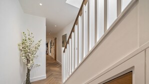 Un interior moderno con piso de madera, paredes blancas y una escalera con barandillas blancas.