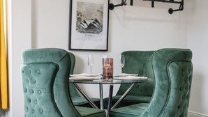 En matplats med två grönklädda stolar, ett glasbord och en inramad karta över Sydney på väggen.