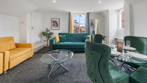 Ett modernt vardagsrum med en grön soffa, en gul fåtölj och ett soffbord i glas.