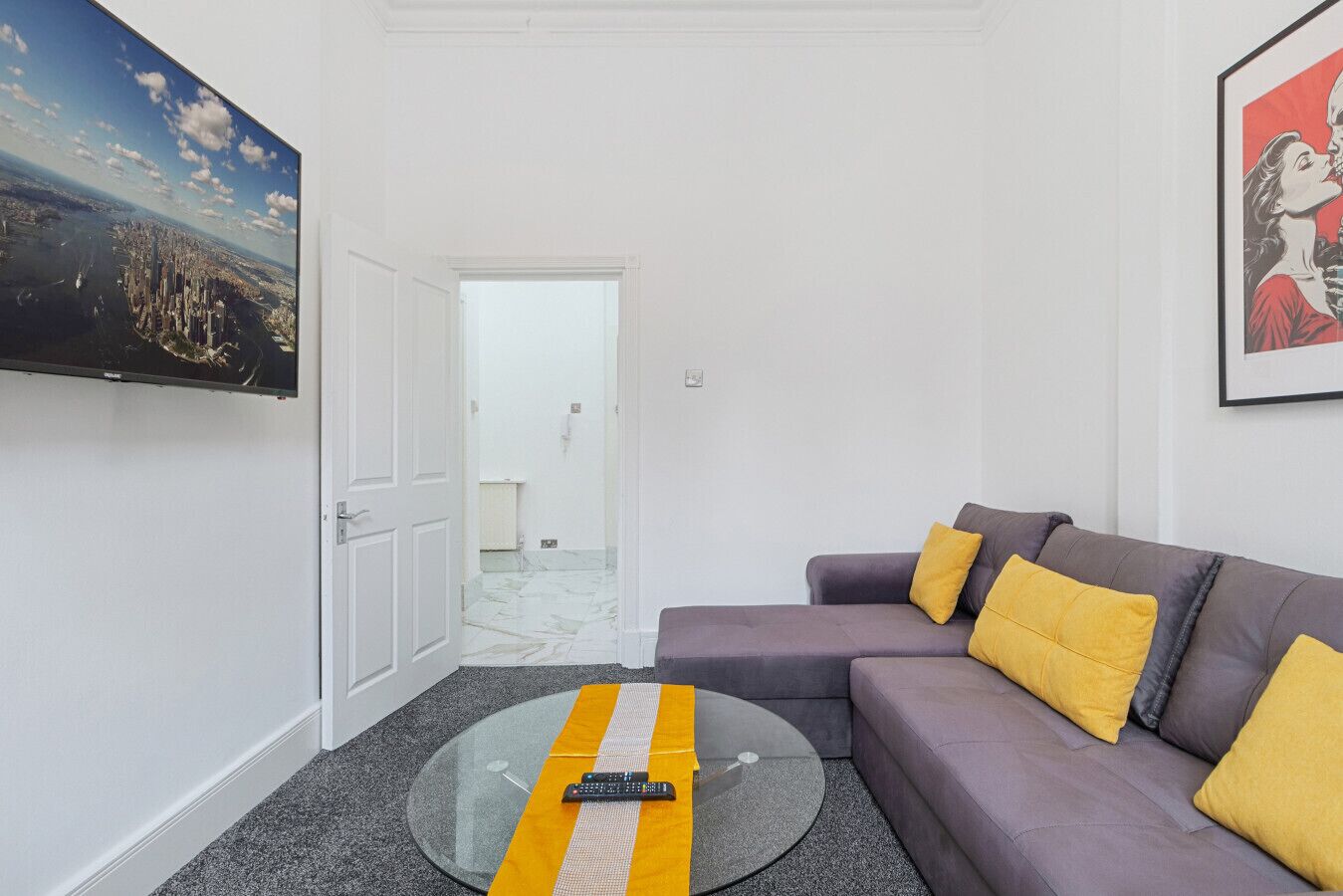 Un salon moderne avec un canapé, une table basse en verre et un tableau accroché au mur.