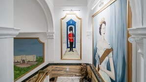 Un couloir orné d’un tableau encadré représentant un bâtiment, une statue et un grand portrait.