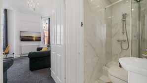 Ein modernes Badezimmer mit einer einbruchsicheren Duschkabine, einer weißen Toilette und einem marmorverlegten Boden.