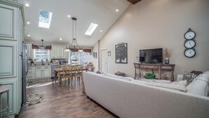 A spacious living area with a high ceiling, wooden beams, and a large window. - New! Charming Home in the Heart of Bemus Point, Lake Chautauqua, NY (Bemus Point)