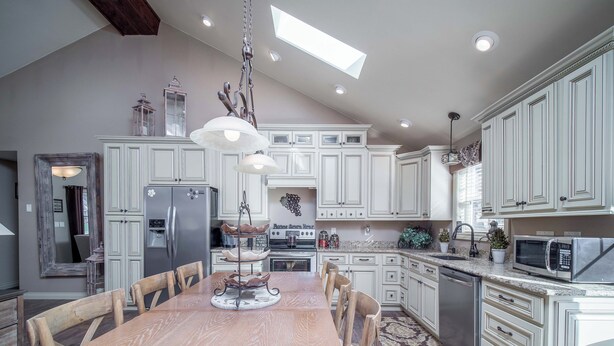 A spacious kitchen with a wooden dining table, white cabinets, and a skylight. - New! Charming Home in the Heart of Bemus Point, Lake Chautauqua, NY (Bemus Point)