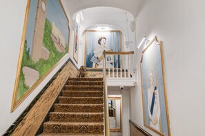 Un magnifique escalier, avec des marches recouvertes d’une moquette richement décorée, menant à un balcon.