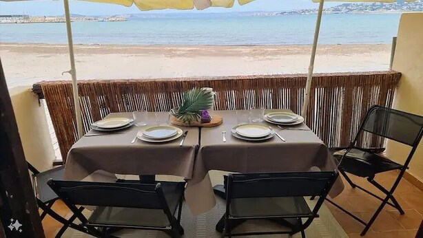 Een eettafel gedekt voor twee personen, met gele parasols, met uitzicht op het strand.