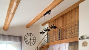 Ein gemütliches Wohnzimmer mit einer Holztreppe, einer großen Wanduhr und einem Sofa mit Kissen.
