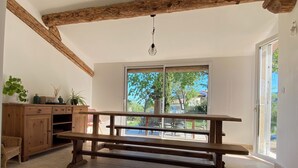 Ein geräumiger Raum mit einer hölzernen Bank, einem Holzschrank und Blick durch ein großes Fenster in einen Außenbereich.