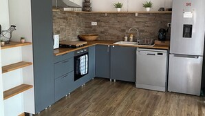 Eine moderne Küche mit grauen Schränken, einer Holz Arbeitsplatte, einem eingebauten Ofen, einem Edelstahl-Kühlschrank und einer Stein-Spritzschutzwand.