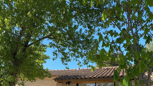 Ein Haus mit einer Terrasse, Sitzgelegenheiten im Freien und einem Grill.