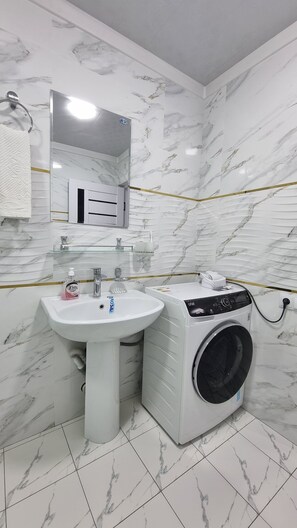 Experience luxurious comfort in this bathroom with a pedestal sink, washing machine, and thoughtful amenities.